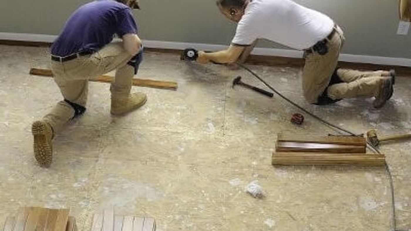 Two workers rebuilding a floor after water damage